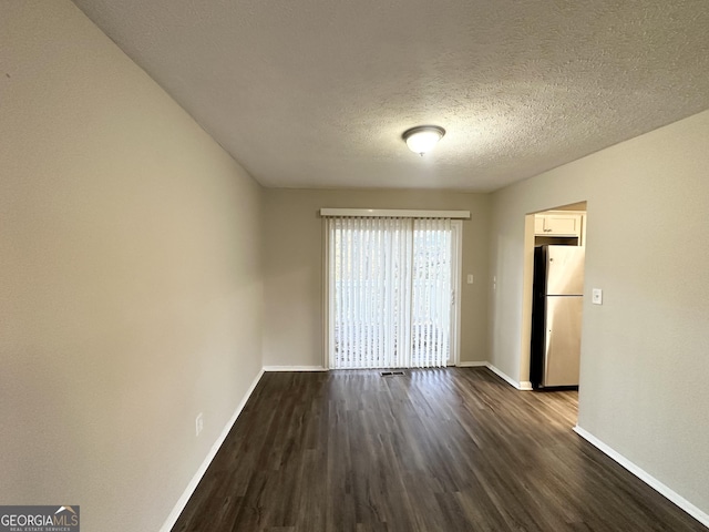 unfurnished room with a textured ceiling and dark wood-type flooring