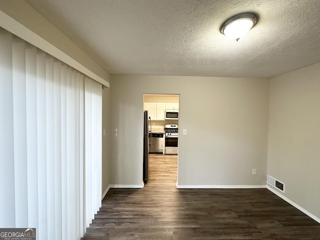 unfurnished room with a textured ceiling and dark hardwood / wood-style floors