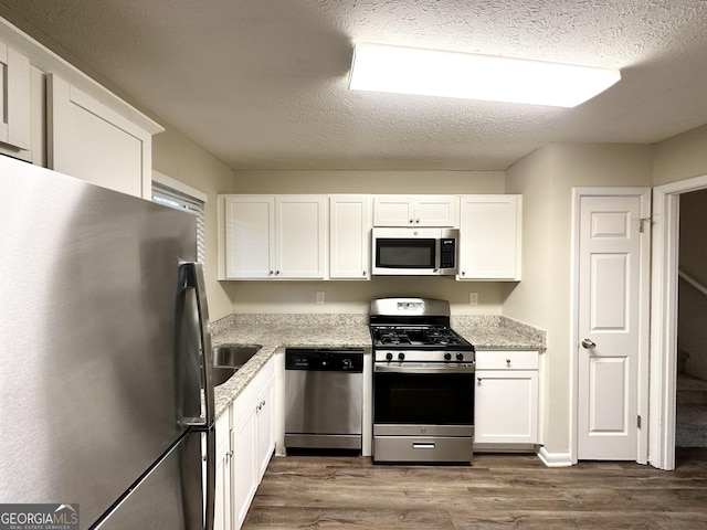 kitchen featuring dark hardwood / wood-style flooring, white cabinets, a textured ceiling, and appliances with stainless steel finishes