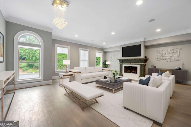 living room featuring a fireplace, an inviting chandelier, ornamental molding, and light wood-type flooring