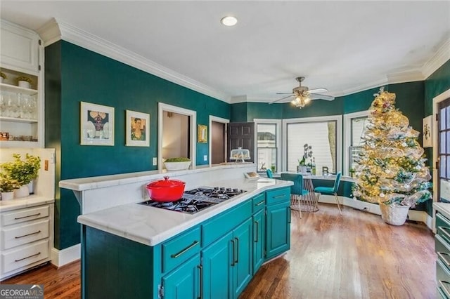 kitchen with a kitchen island, dark hardwood / wood-style flooring, ornamental molding, stainless steel gas stovetop, and blue cabinets