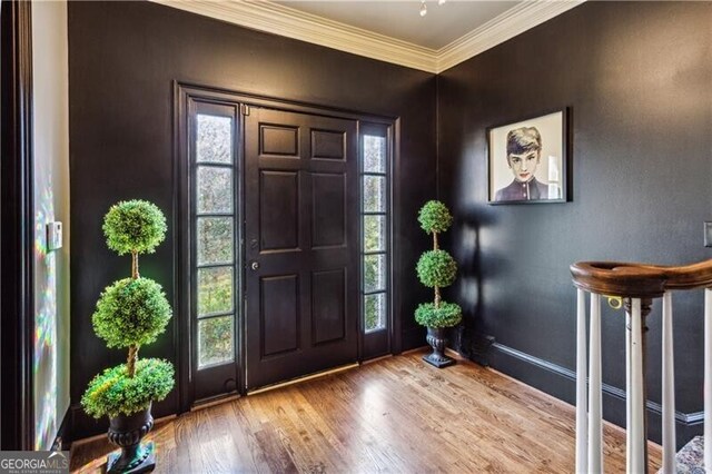 stairway with ornamental molding and hardwood / wood-style floors