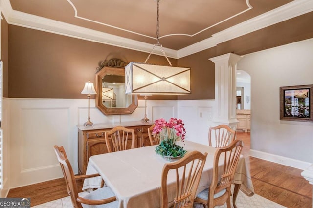 dining room with decorative columns, crown molding, and light hardwood / wood-style flooring