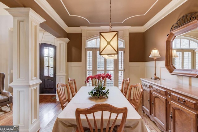 dining space with decorative columns, light hardwood / wood-style flooring, and ornamental molding