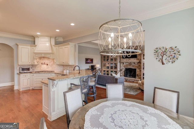 dining area featuring a chandelier, crown molding, a fireplace, and light hardwood / wood-style flooring