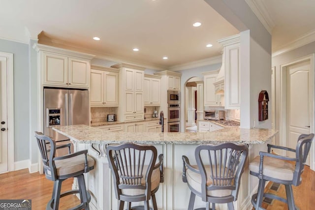 kitchen featuring decorative backsplash, a kitchen bar, kitchen peninsula, and light hardwood / wood-style flooring