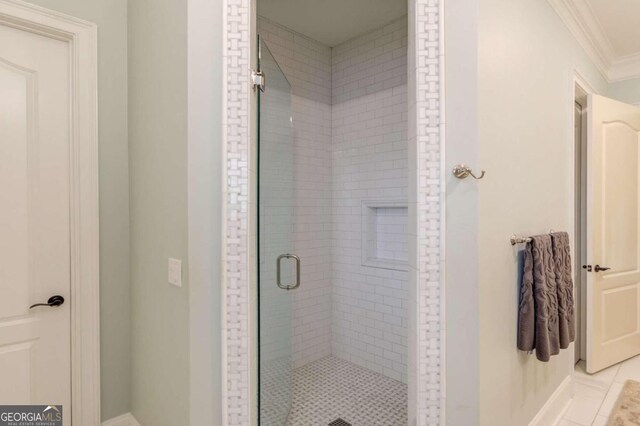 bathroom featuring tile patterned floors, a shower with shower door, and ornamental molding