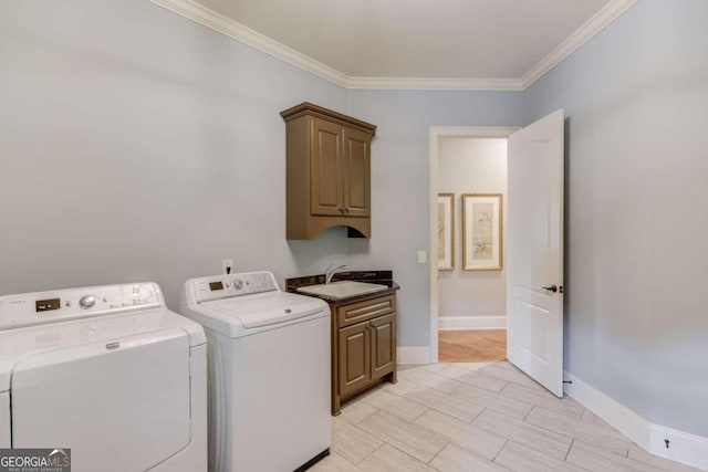 clothes washing area featuring washer and clothes dryer, sink, cabinets, and ornamental molding