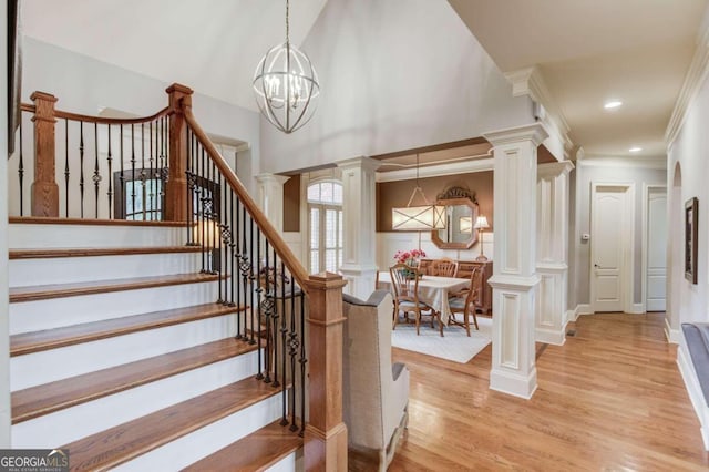 staircase with hardwood / wood-style flooring, crown molding, and an inviting chandelier