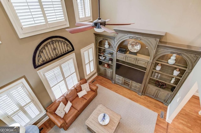 living room featuring ceiling fan, hardwood / wood-style floors, and a high ceiling