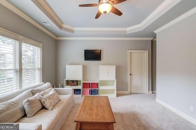 carpeted living room featuring a tray ceiling, ceiling fan, and ornamental molding