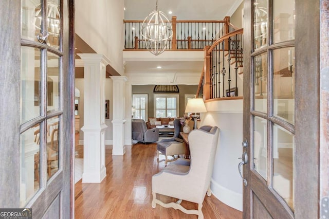 foyer entrance featuring light hardwood / wood-style floors, french doors, crown molding, and decorative columns