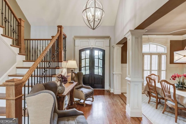 foyer featuring french doors, decorative columns, a notable chandelier, and wood-type flooring