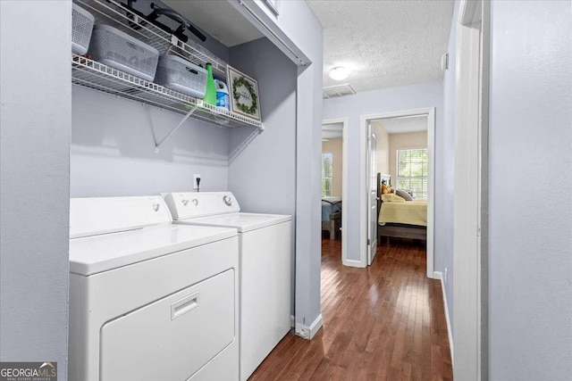 laundry room with a textured ceiling, dark wood-type flooring, and washing machine and clothes dryer