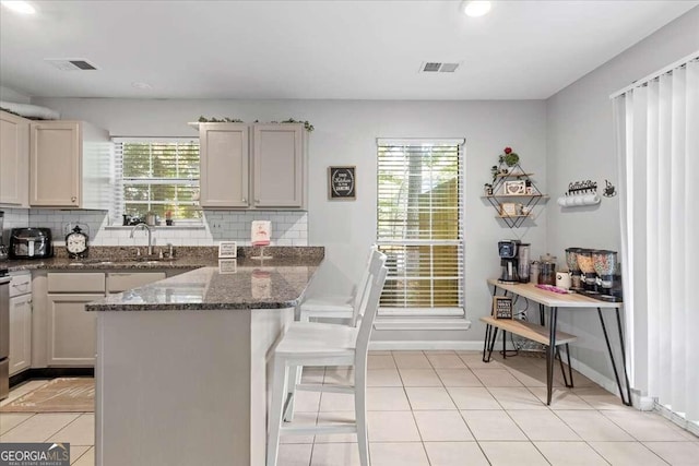 kitchen with a healthy amount of sunlight, dark stone countertops, sink, and tasteful backsplash