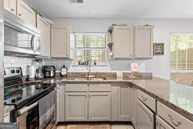 kitchen featuring decorative backsplash, appliances with stainless steel finishes, dark stone counters, and sink