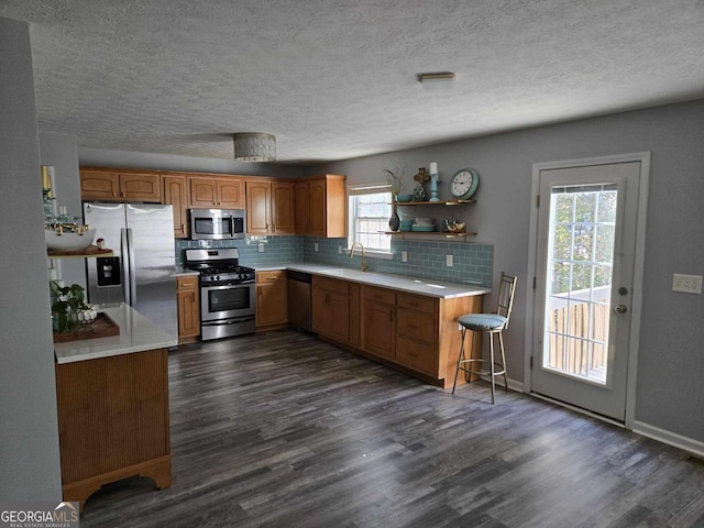 kitchen with sink, tasteful backsplash, dark hardwood / wood-style flooring, a textured ceiling, and appliances with stainless steel finishes