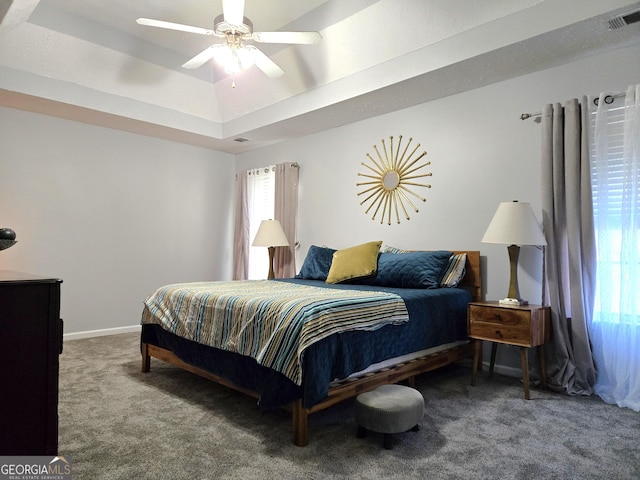 bedroom with carpet, a tray ceiling, and ceiling fan