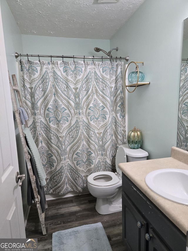 bathroom featuring vanity, toilet, a textured ceiling, walk in shower, and wood-type flooring