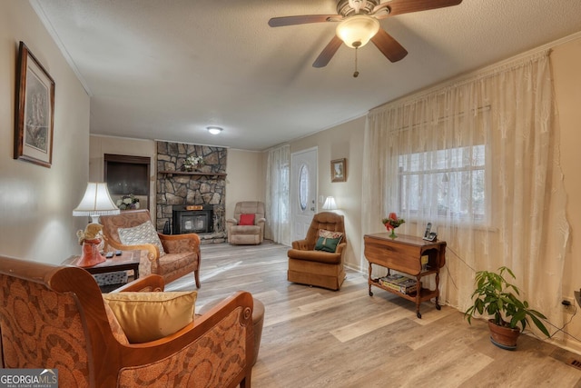 living room with ceiling fan, crown molding, a textured ceiling, and light wood-type flooring