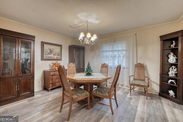 dining area featuring a notable chandelier, light hardwood / wood-style floors, ornamental molding, and a textured ceiling