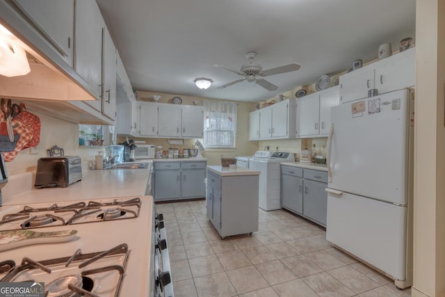 kitchen featuring white appliances, ceiling fan, separate washer and dryer, a kitchen island, and light tile patterned flooring