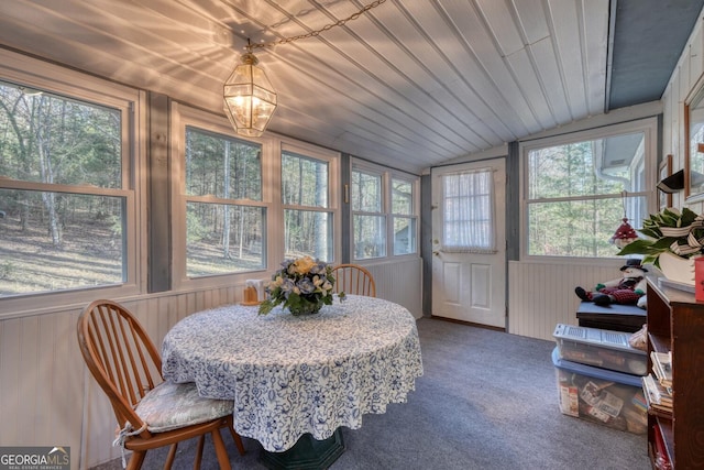 sunroom with vaulted ceiling, a healthy amount of sunlight, and a notable chandelier