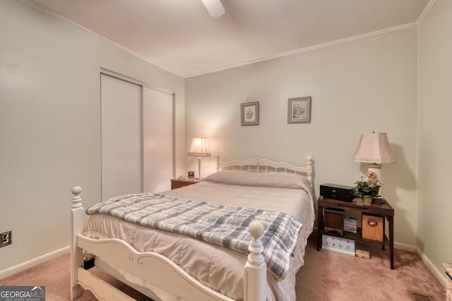 carpeted bedroom featuring ceiling fan, crown molding, and a closet