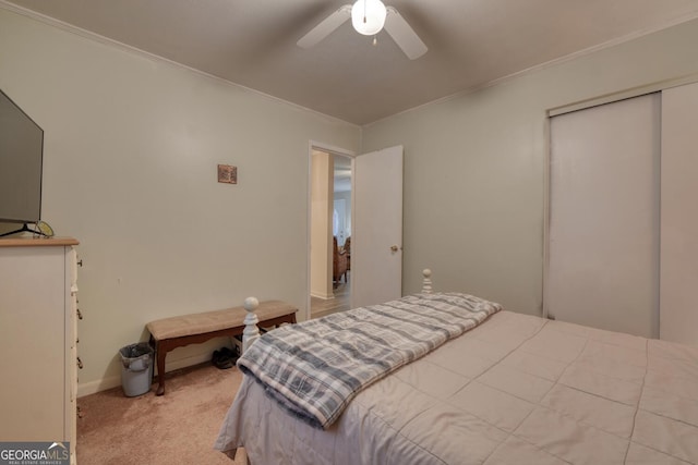 carpeted bedroom with a closet, ceiling fan, and ornamental molding