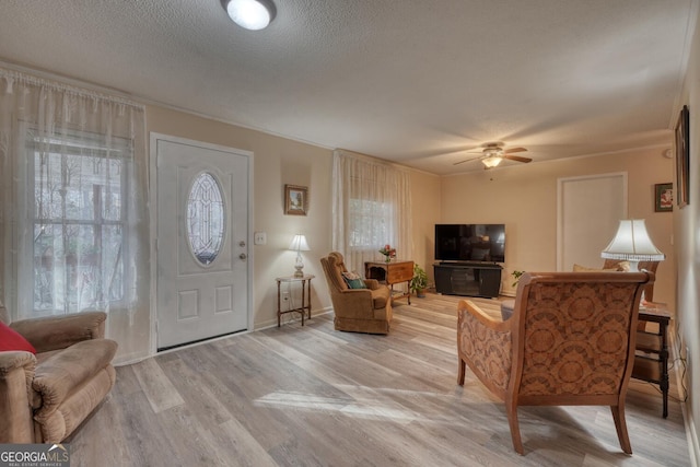 entrance foyer featuring a textured ceiling, light hardwood / wood-style floors, ceiling fan, and crown molding