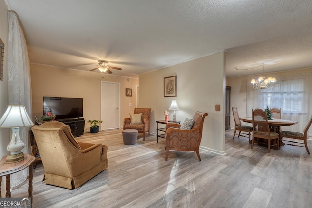 living room featuring hardwood / wood-style floors, ceiling fan with notable chandelier, ornamental molding, and a textured ceiling