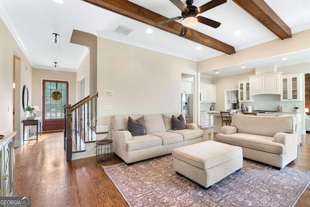 living room with beam ceiling, crown molding, ceiling fan, and dark wood-type flooring