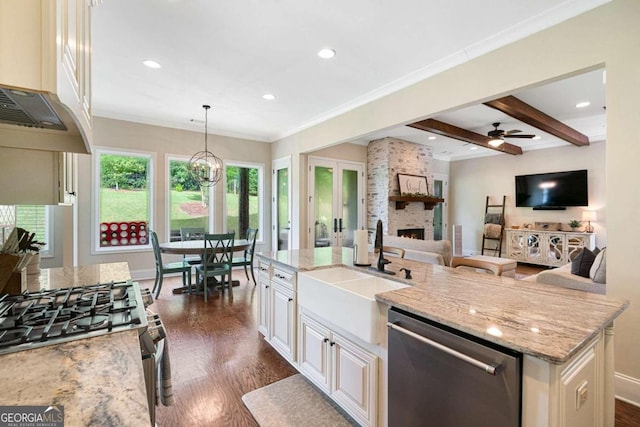 kitchen featuring appliances with stainless steel finishes, dark wood-type flooring, sink, hanging light fixtures, and an island with sink