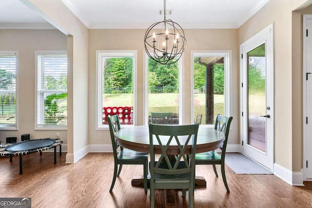 dining space featuring crown molding, a notable chandelier, and hardwood / wood-style flooring