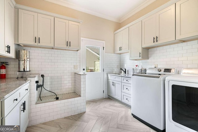 laundry area featuring cabinets, sink, washer and dryer, ornamental molding, and light parquet flooring