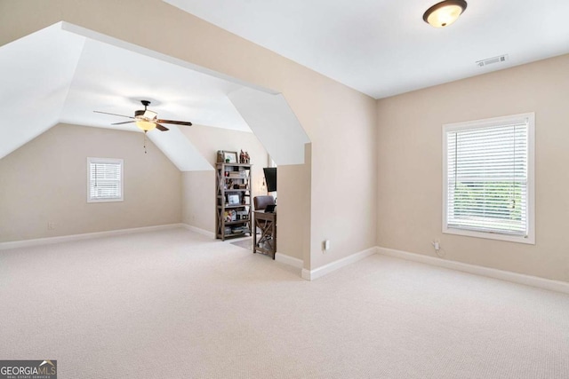 additional living space with light colored carpet, vaulted ceiling, ceiling fan, and a healthy amount of sunlight