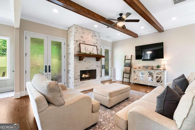 living room with ceiling fan, french doors, beamed ceiling, wood-type flooring, and a fireplace