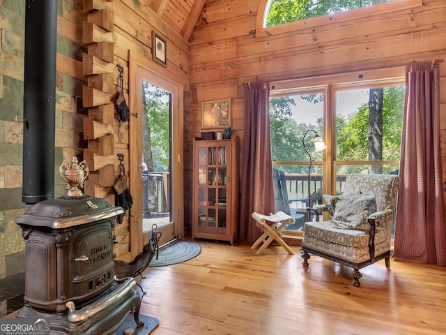 sitting room with plenty of natural light, wood walls, light wood-type flooring, and a wood stove