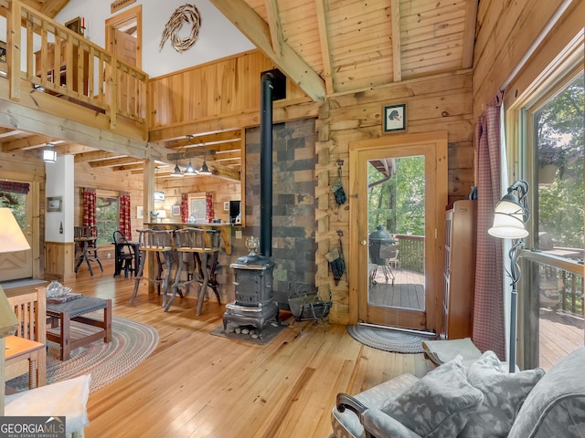 living room with beam ceiling, a wood stove, wood walls, and hardwood / wood-style floors