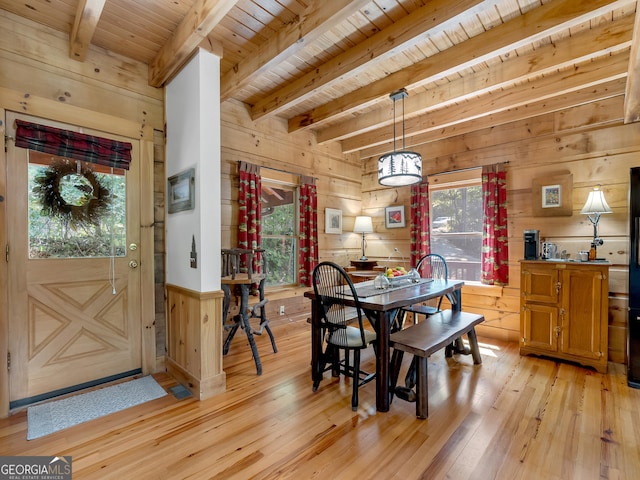 dining area with beamed ceiling, light hardwood / wood-style floors, wooden ceiling, and wooden walls