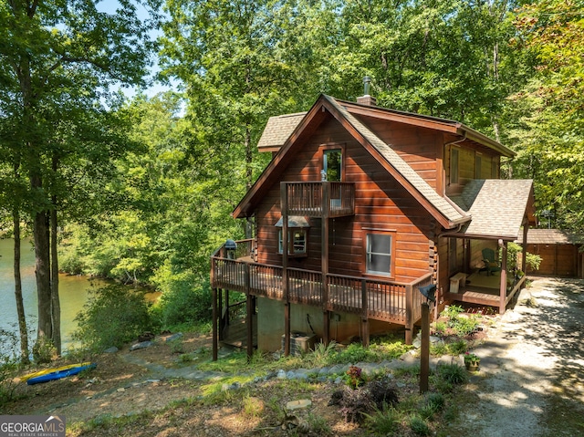 rear view of property featuring central AC unit and a deck with water view