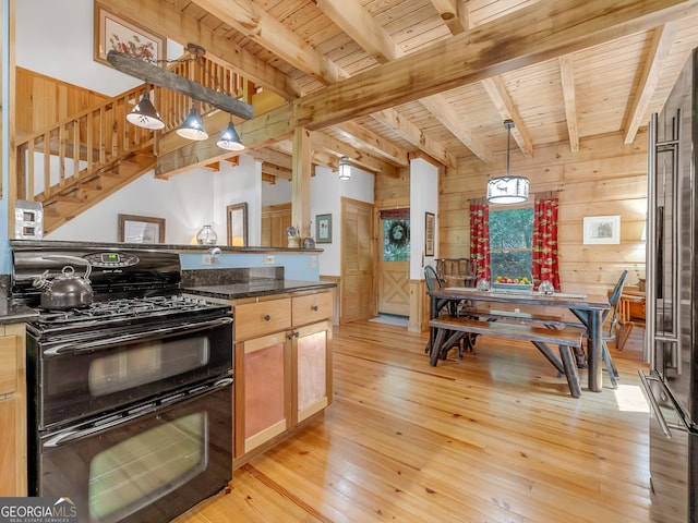 kitchen with black stove, light brown cabinetry, beam ceiling, light hardwood / wood-style floors, and hanging light fixtures