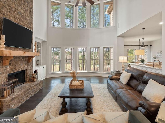 living room with dark hardwood / wood-style floors, a brick fireplace, and plenty of natural light