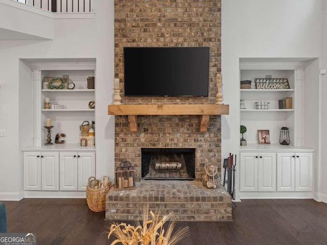 living room with a fireplace, built in features, and dark wood-type flooring