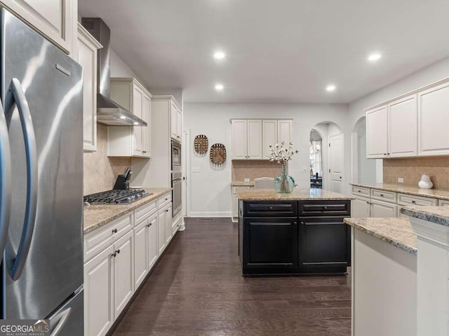 kitchen featuring decorative backsplash, appliances with stainless steel finishes, dark hardwood / wood-style flooring, light stone countertops, and white cabinets