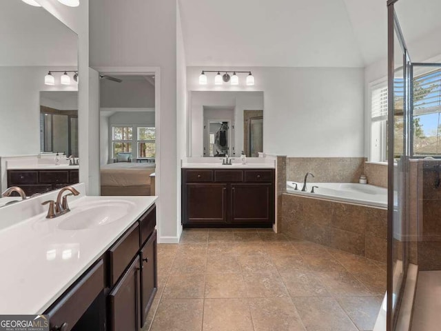 bathroom featuring vanity, a relaxing tiled tub, vaulted ceiling, and plenty of natural light