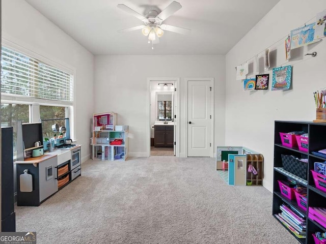 recreation room with ceiling fan and light colored carpet