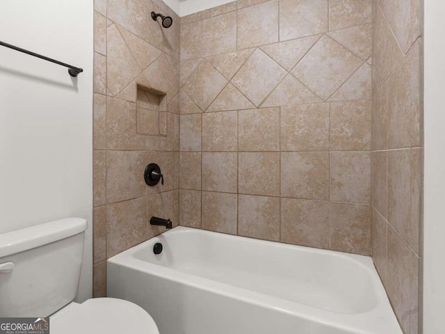 bathroom featuring tiled shower / bath combo and toilet