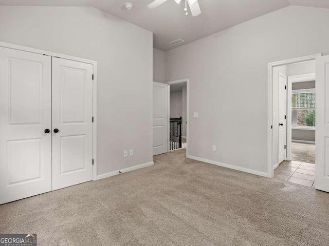 unfurnished bedroom with ceiling fan, lofted ceiling, light carpet, and a closet