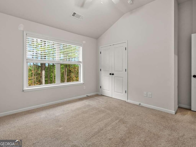 unfurnished bedroom featuring light carpet, a closet, vaulted ceiling, and ceiling fan